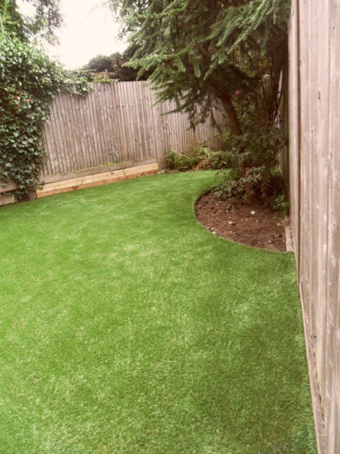 Clean, freshly groomed artificial grass lawn in a fenced backyard